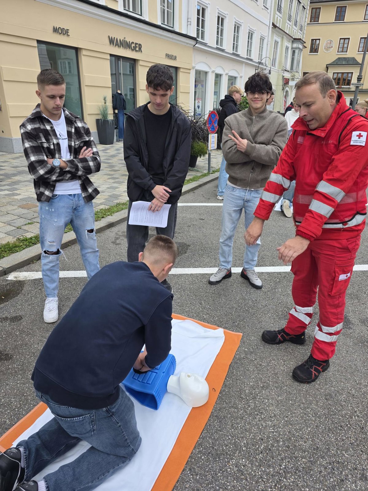 Erste Hilfe Kurs: Mann übt Reanimation an Übungspuppe in der Fußgängerzone von Wels.